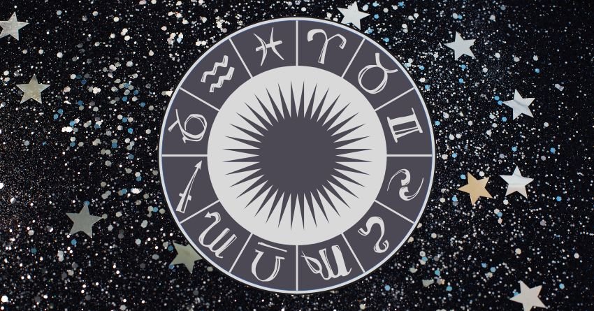 Glowing silver zodiac wheel surrounded by sparkling stars against a dark cosmic background