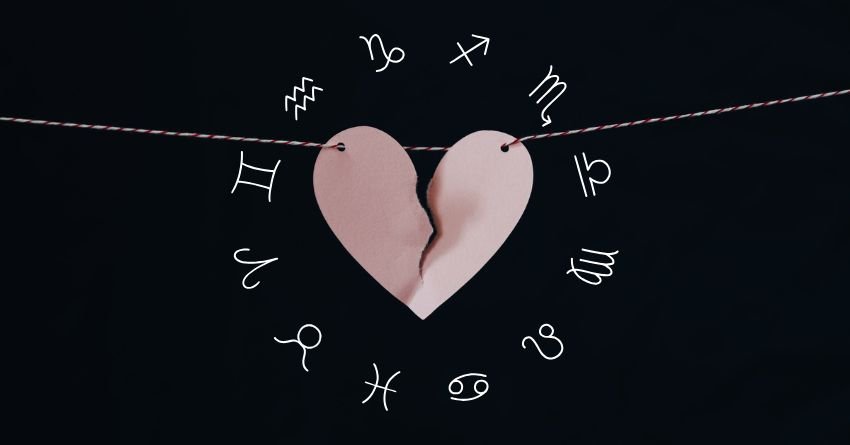 Pink broken heart surrounded by zodiac symbols against a dark background