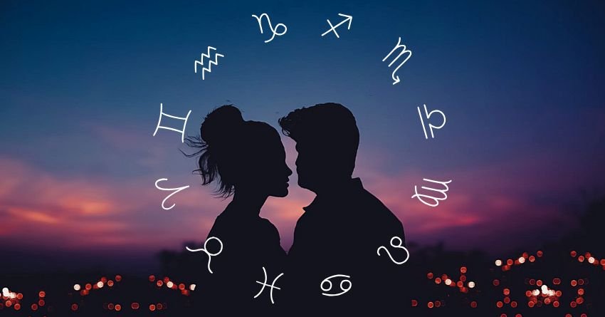 Silhouetted couple beneath zodiac symbols and stars against a colorful twilight sky