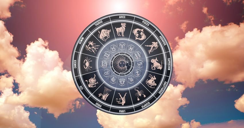 Silver zodiac wheel surrounded by pink and orange clouds in a glowing sky