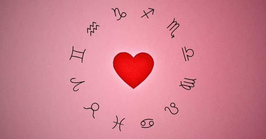 Bright red heart surrounded by zodiac symbols on a soft pink background, representing love, happiness, and positive energy