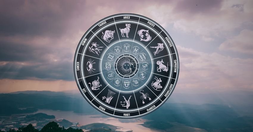 Silver zodiac wheel above a dark ocean under a dramatic cloudy sky