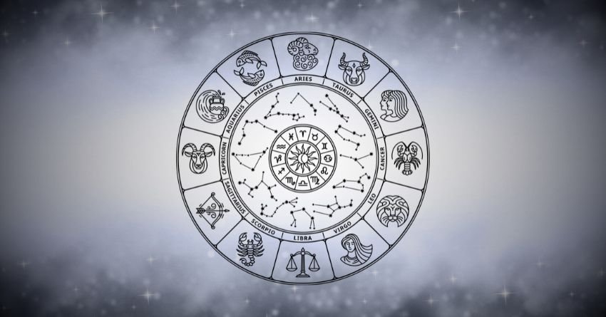 Silver zodiac wheel glowing against a soft white and gray cosmic background with misty clouds